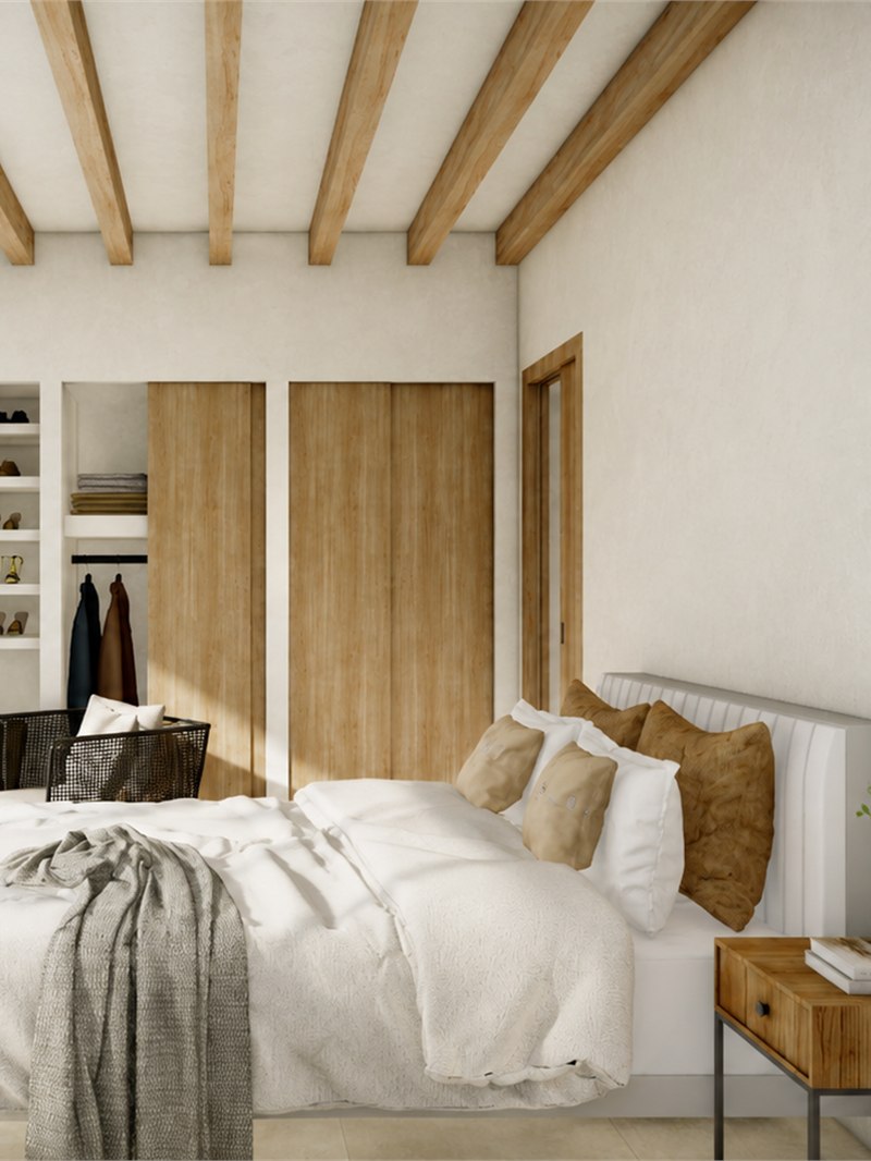 Dormitorio con frente de armarios de madera y el vestidor abierto a un lado, con la cama vestida en blanco y cojines de cuero
