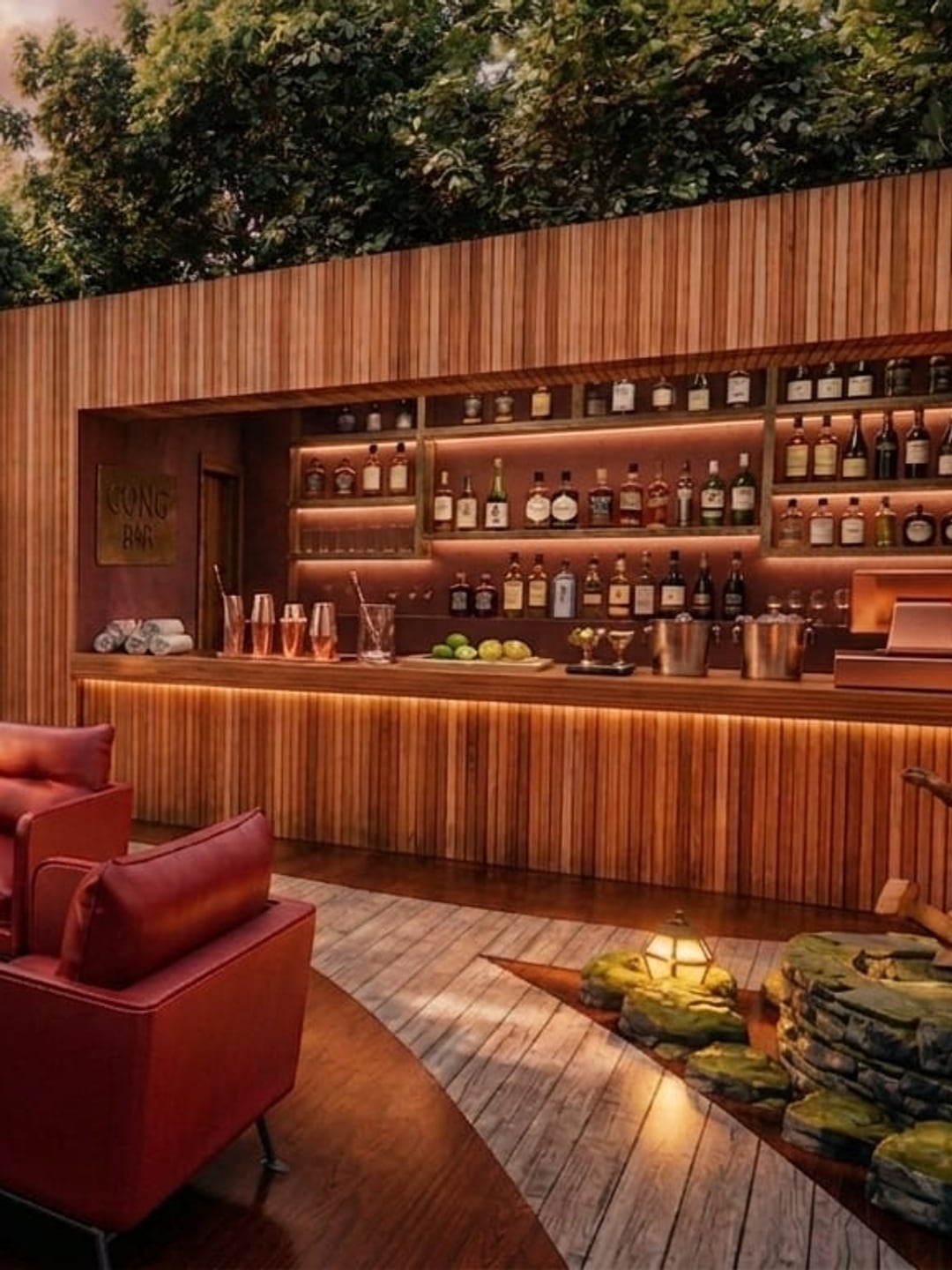 El mostrador de madera con la estantería de botellas iluminada detrás, y en primer término un sillón rojo junto a las piedras de musgo